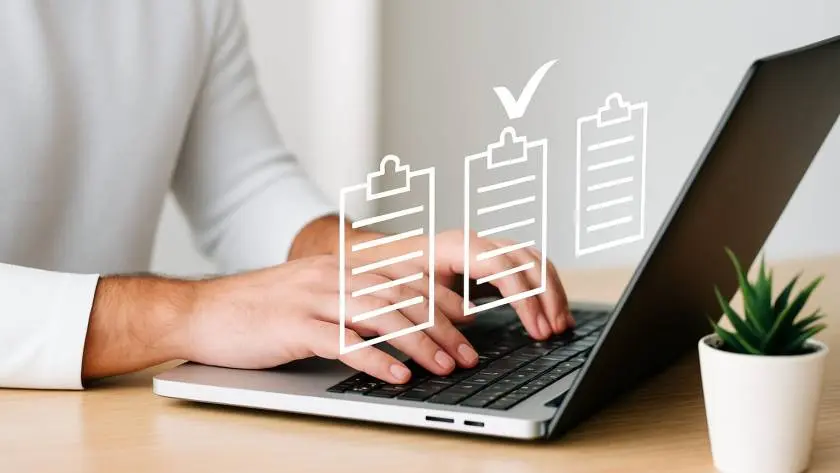 Man typing on laptop at wooden desk with floating digital checklist icons — concept of compliance and task completion.